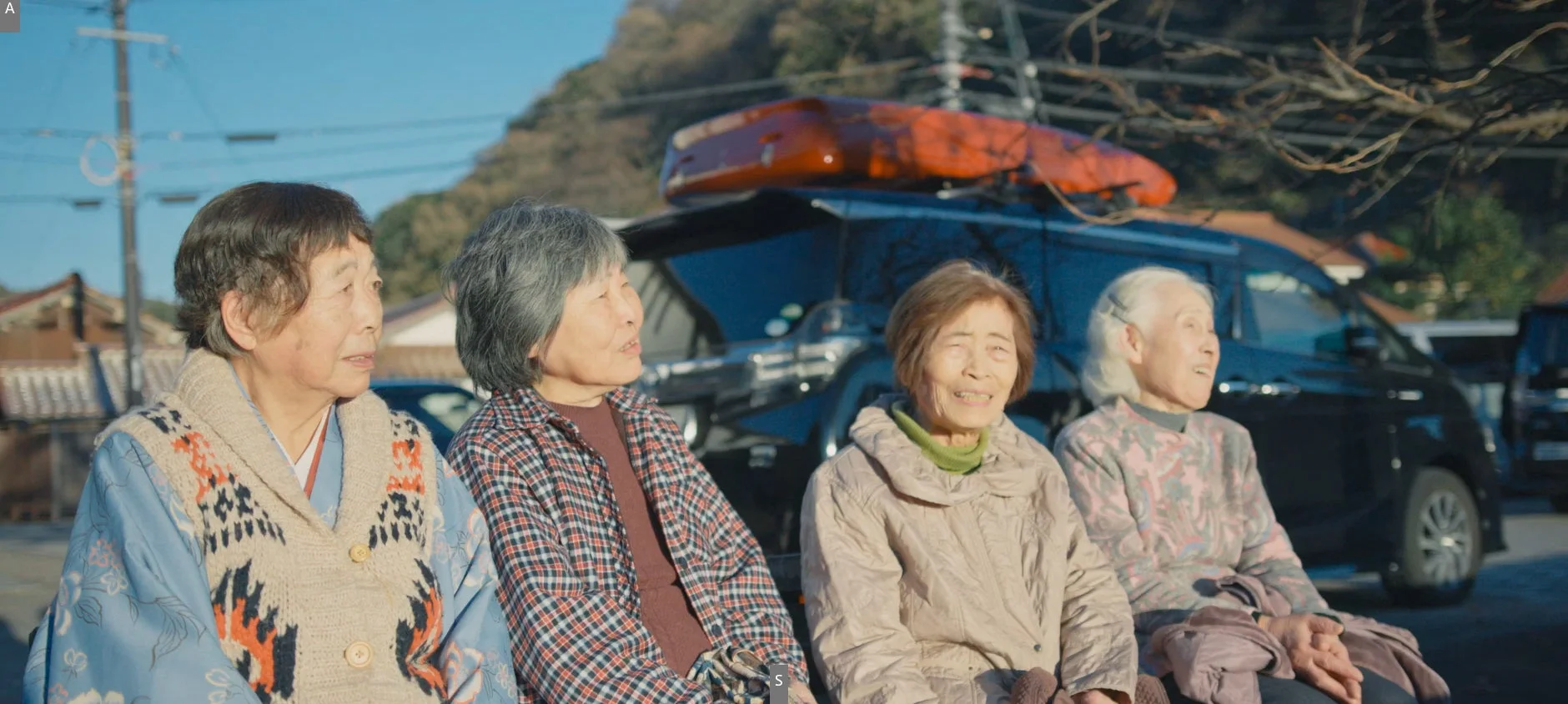 高齢女性がバンを背景に談笑