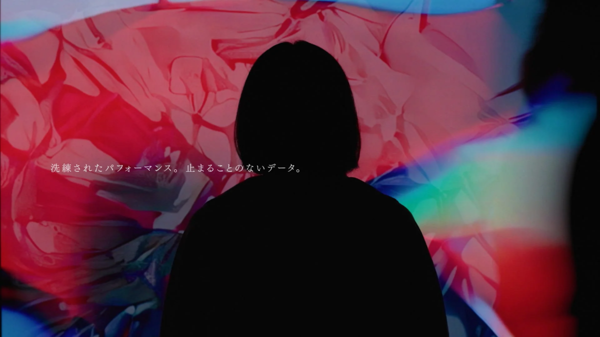 人物のシルエットが、赤や青の抽象的な光の背景に映し出されています