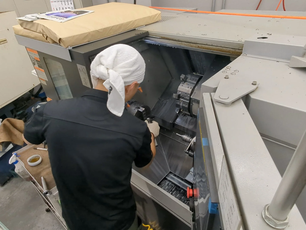 工場内で作業員が旋盤のような大型機械を操作している様子