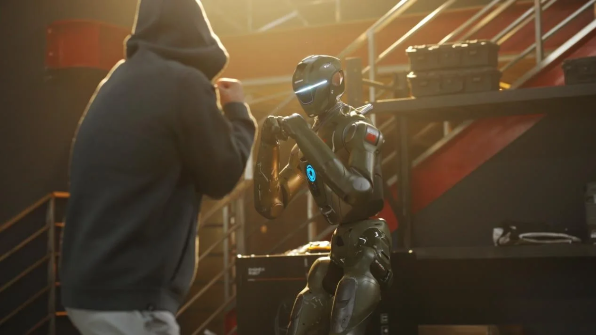 フードをかぶった人物とロボットがボクシングのような構えで対峙している