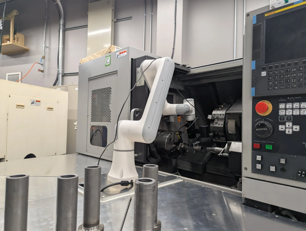 産業用ロボットアームがCNC旋盤と連携して作業する製造現場の様子