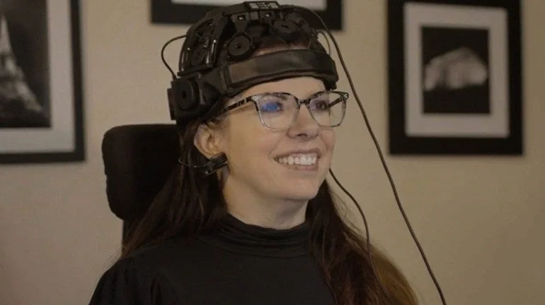 脳波測定用のヘッドセットを装着し、笑顔を見せる女性のポートレート。