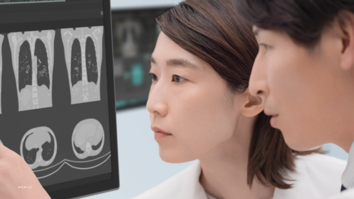 二人の医療従事者が、モニターに表示された肺のCTスキャン画像を真剣な表情で確認している様子です。医療現場での診断や研究を示唆する場面です。