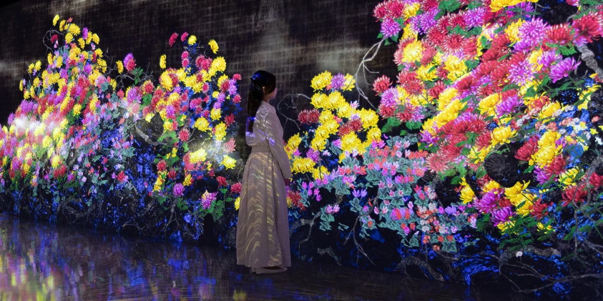 色鮮やかな菊のデジタルアートインスタレーションの前に立つ女性