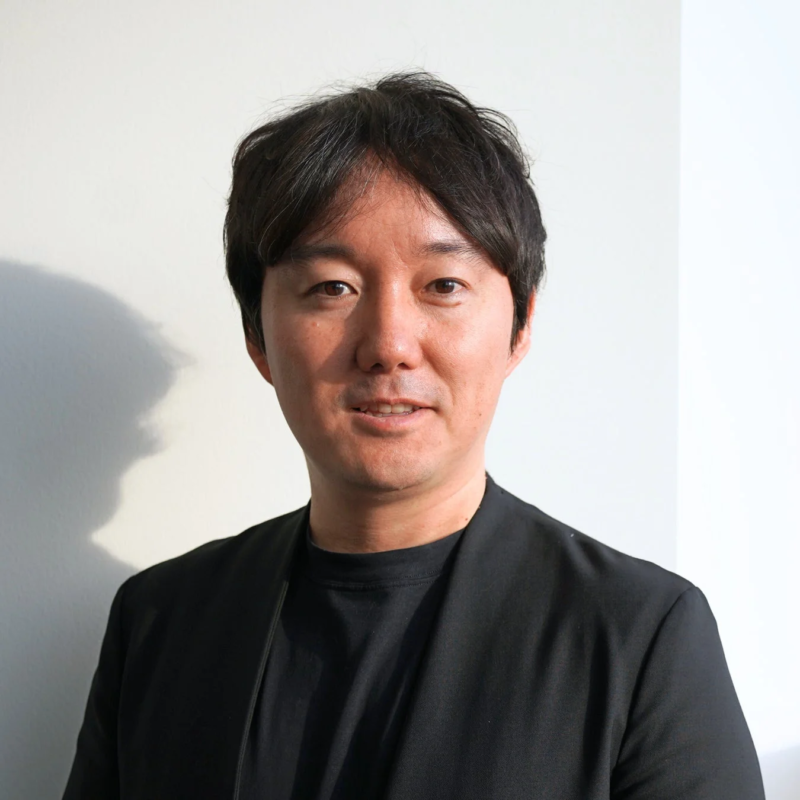 黒い服を着た日本人男性が微笑んでいるポートレート写真