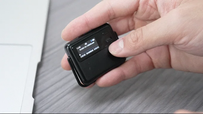 小型の黒いデジタルボイスレコーダーを操作している様子