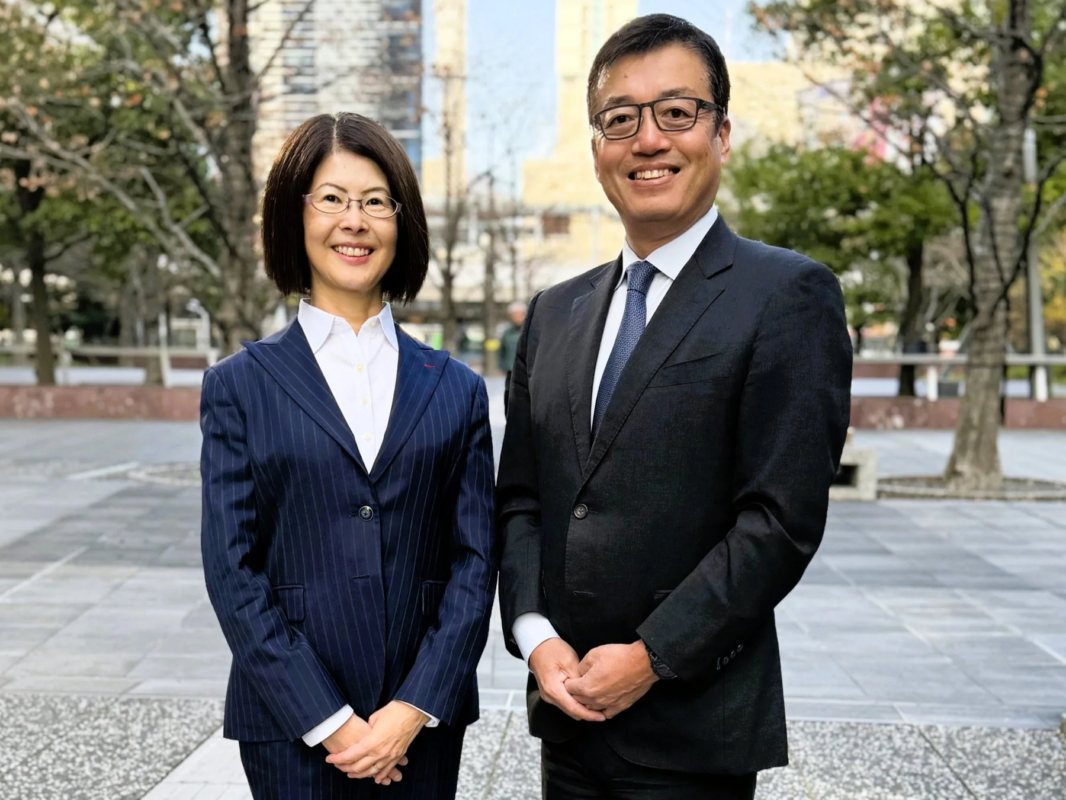 ビジネススーツを着用した男女が屋外で笑顔を見せている様子