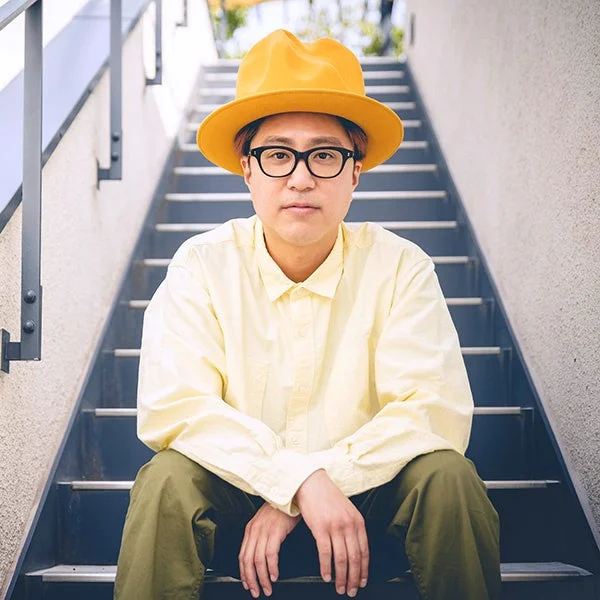 黄色い帽子と眼鏡をかけた男性が階段に座っているポートレート