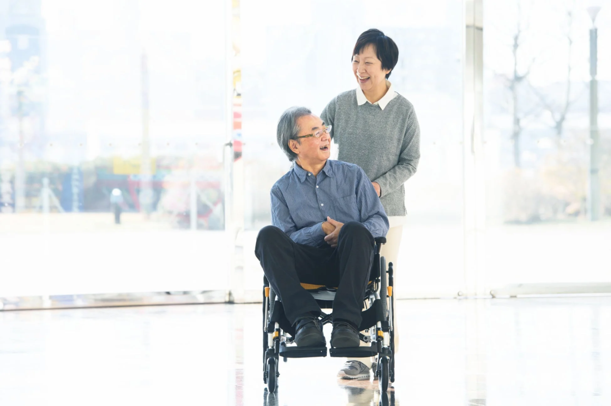 車椅子に座る高齢男性と話す女性