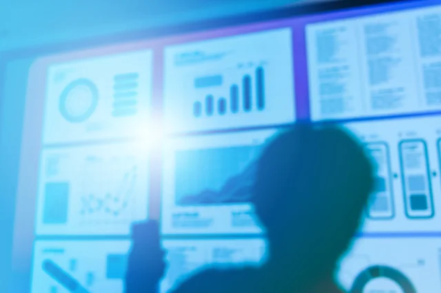 データ分析やグラフを眺める人物のシルエット