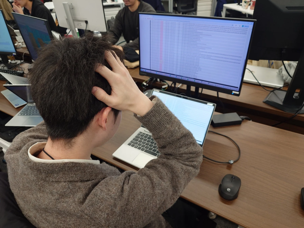 オフィスでパソコンに向かい、複数のモニターを見つめる人物