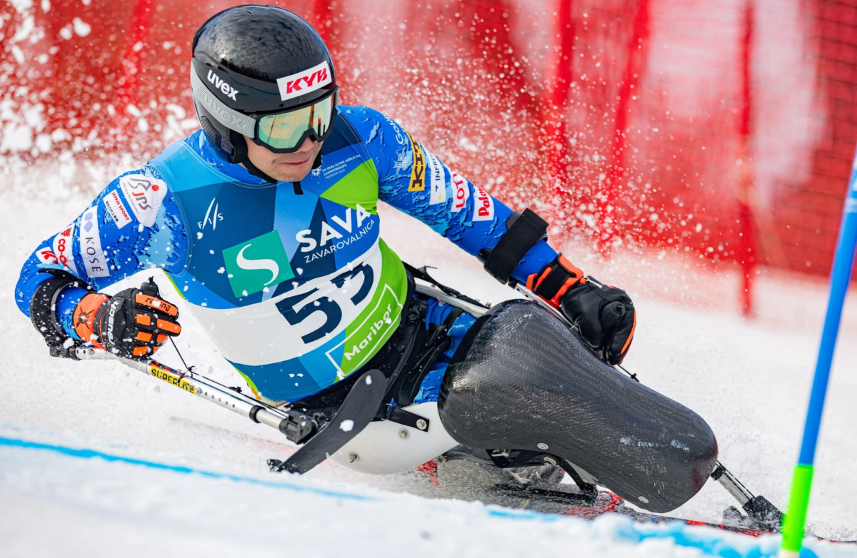 チェアスキーの選手が雪しぶきを上げながら急斜面を滑走している